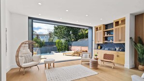 A modern living room with a large glass door leading to a patio area. - Venice Open Designer House w Pool (Los Angeles)