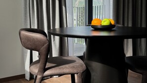 A modern dining area with a round table, two chairs, and a bowl of fruit. - Hvanndalir Lodge (Olafsfjordur)