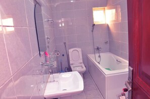 A bathroom with a bathtub, a toilet, and a sink. - Mimantex Apartment (Abuja)