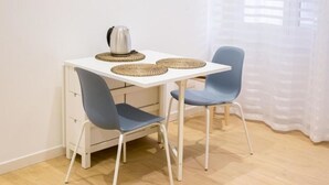 A small, white desk with two blue chairs, a silver kettle, and woven placemats. - RoomApartment Rome: 1 Bedroom Apartment with Balcony  (Roma)