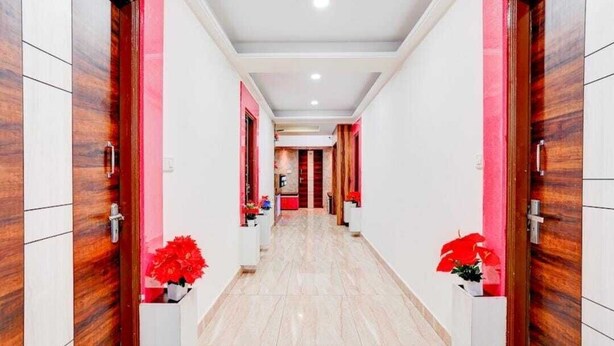 A hotel corridor with wooden doors, white walls, and red accents. - Shravanya Comforts (Bengaluru)