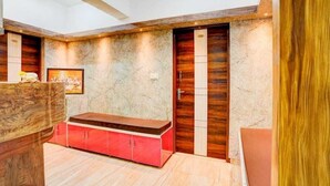 A modern interior with a wooden bench, a red cabinet, and a door with a vertical panel design. - Shravanya Comforts (Bengaluru)