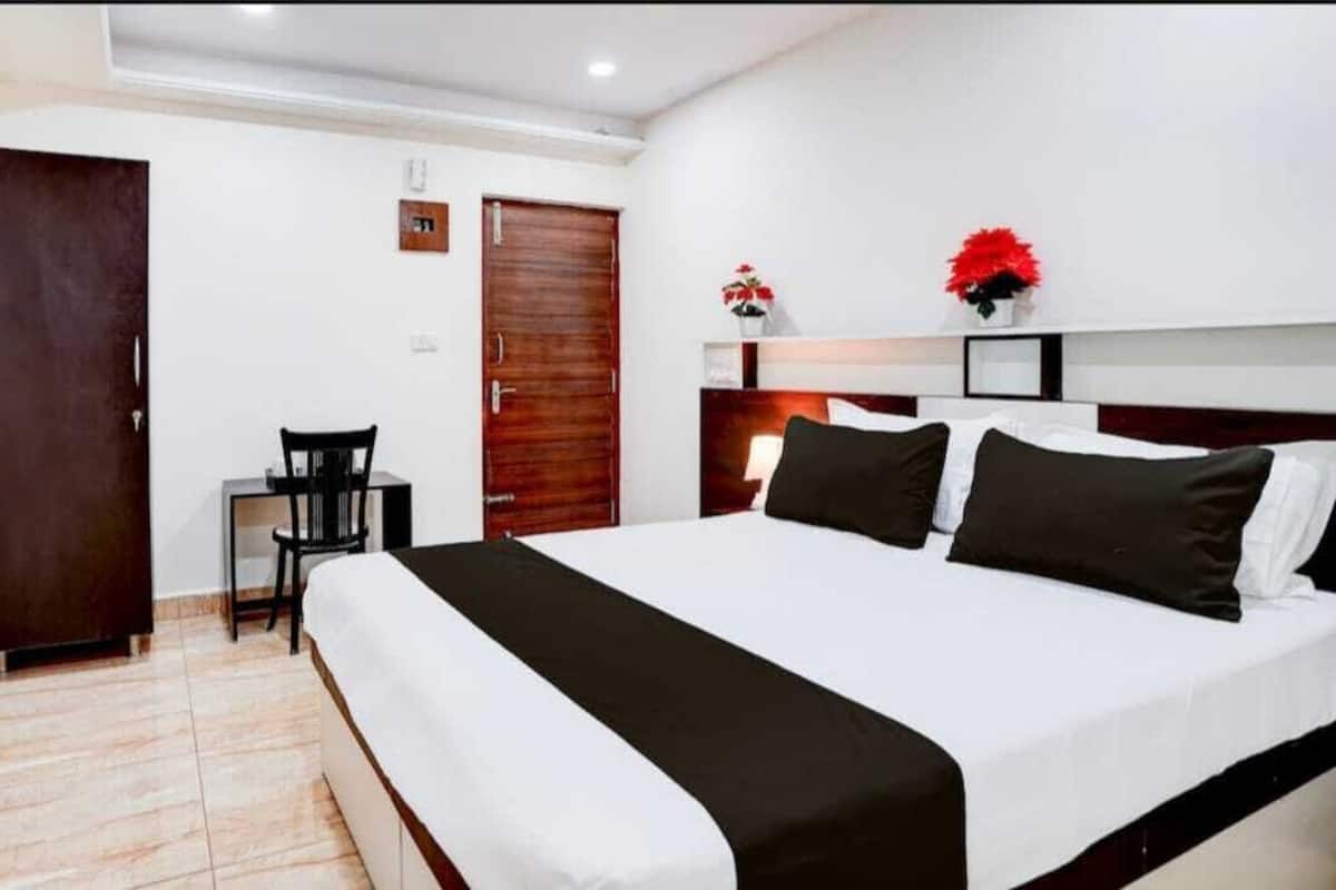 A hotel room with a large bed, a desk, a chair, and a wardrobe.