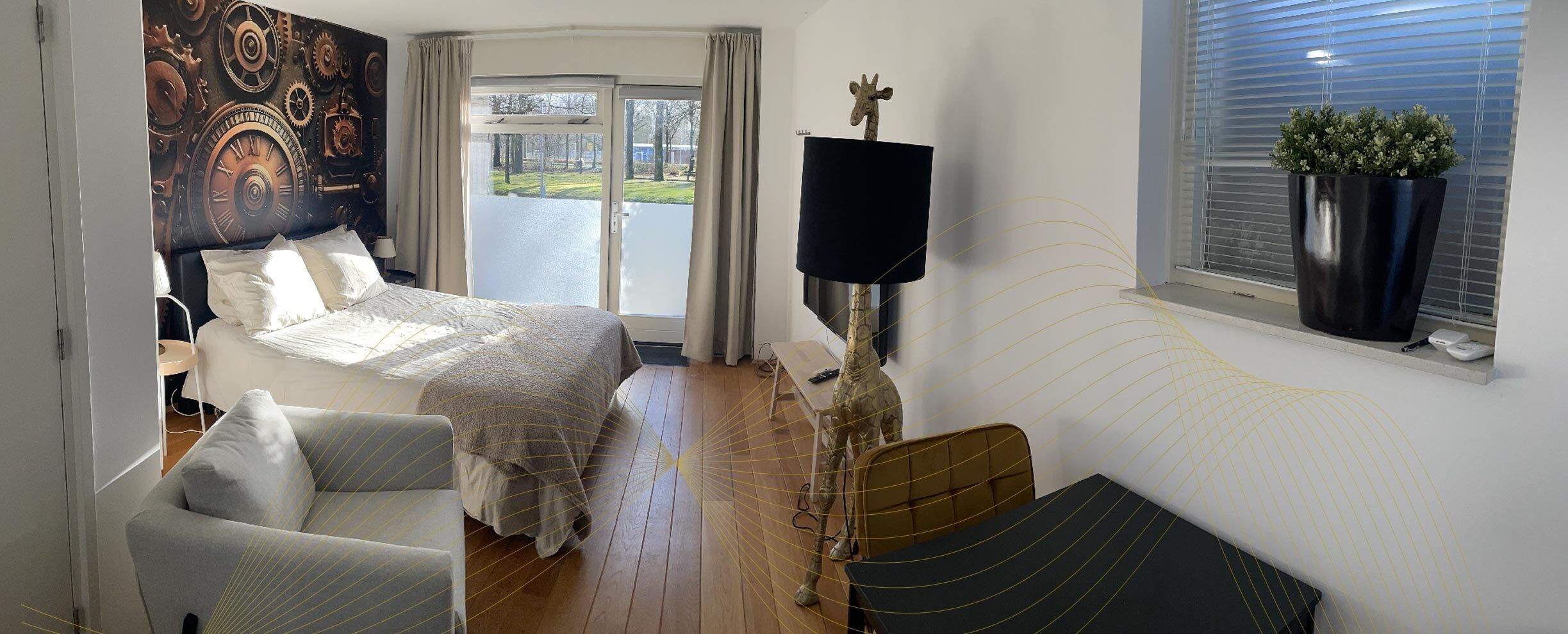 Une chambre à coucher avec un lit, une chaise, un téléviseur et une fenêtre agrémentée d’une plante.