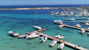 A marina with numerous boats docked, clear turquoise water, and a long pier extending into the sea. - Cozy little house in Otranto, in the beautiful Baia dei Turchi. Pet Friendly. (Puglia)