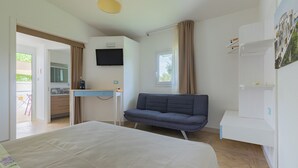 A modern hotel room with a bed, a sofa, a desk, and a TV mounted on the wall. - Cozy little house in Otranto, in the beautiful Baia dei Turchi. Pet Friendly. (Puglia)