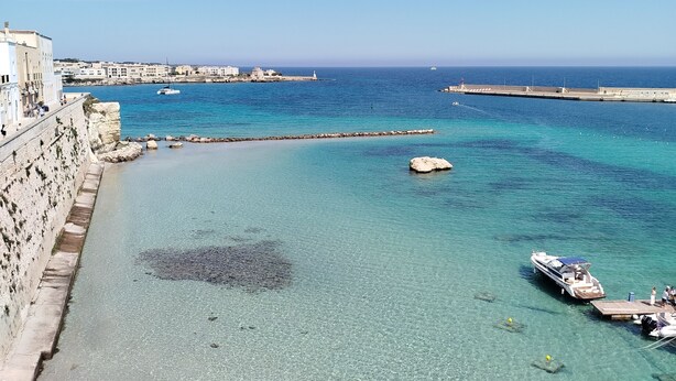 A coastal town with clear turquoise waters, a rocky shoreline, and a pier extending into the sea. - Cozy little house in Otranto, in the beautiful Baia dei Turchi. Pet Friendly. (Puglia)