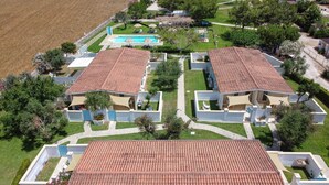 A residential area with two buildings featuring red-tiled roofs, a swimming pool, and surrounding greenery. - Cozy little house in Otranto, in the beautiful Baia dei Turchi. Pet Friendly. (Puglia)