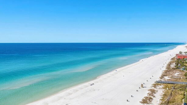 Une vaste plage aux eaux turquoise et limpides, bordée d’un rivage sablonneux.