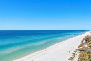 A wide beach with clear turquoise waters and a sandy shore.