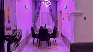 A dining area with a table and chairs, a fan, and a chandelier. - PrimeAxis Apartment (Ilorin)