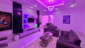 A modern living room with a flat-screen TV, a sofa, a coffee table, and a decorative plant. - PrimeAxis Apartment (Ilorin)