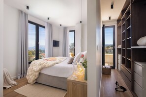 Une chambre à coucher avec un lit, une table de chevet, des rideaux, un téléviseur et une vue sur l’extérieur.