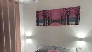 Een moderne slaapkamer met een bed, een schilderij en twee wandlampen.