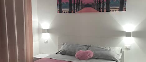 A modern bedroom with a bed, a painting, and two wall-mounted lights.