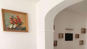 Een moderne vergaderruimte met een witte tafel, grijze stoelen en een bloemen schilderij aan de muur.