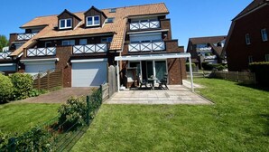 A two-story residential building with a covered patio area, a brick facade, and a garage. - Vacation apartment 5 minutes from the sea, with dog. (Schönberg)