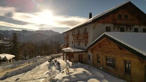 A two-story wooden chalet with a balcony, set against a mountainous backdrop. - Hôtel des Muverans (Leytron)