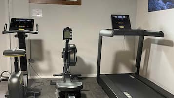 Een fitnessruimte met cardiotoestellen, gewichten en een loopband.
