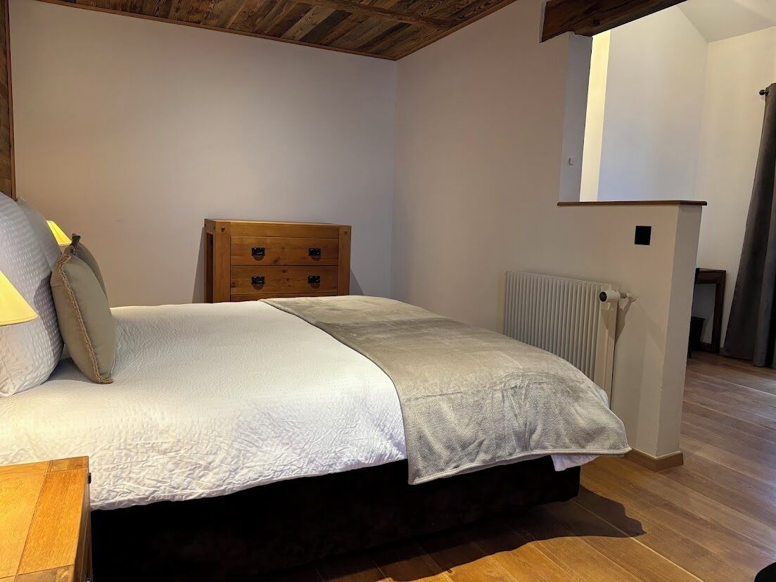 Un dormitorio con cama, cabecero de madera, mesita de noche y radiador.