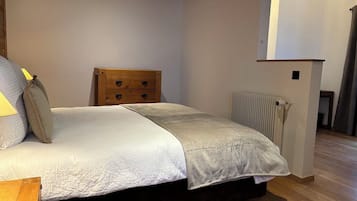 Un dormitorio con cama, cabecero de madera, mesita de noche y radiador.