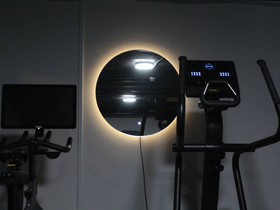 A stationary bike with a digital display and a wall-mounted mirror.