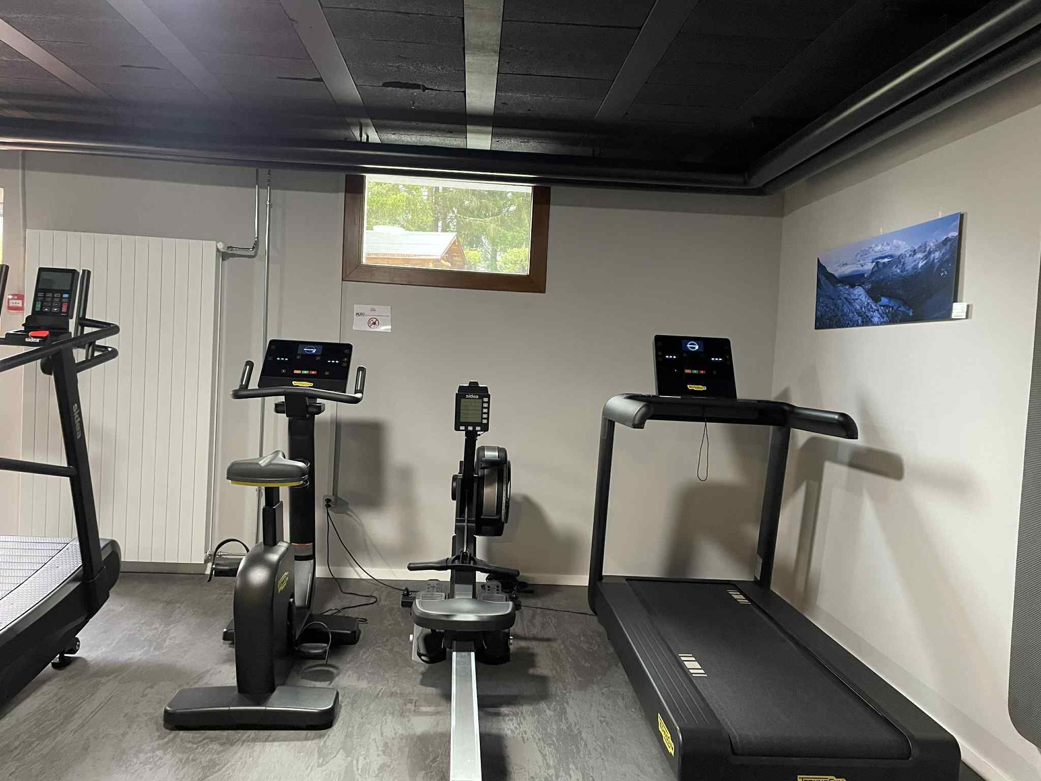 Een fitnessruimte met loopbanden, een elliptische trainer en een hometrainer, voorzien van digitale displays.