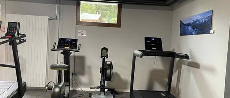 Een fitnessruimte met loopbanden, een elliptische trainer en een hometrainer, voorzien van digitale displays.