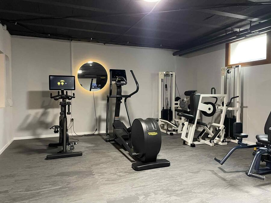 Un gimnasio con equipo de ejercicio, un espejo y un monitor de televisión.