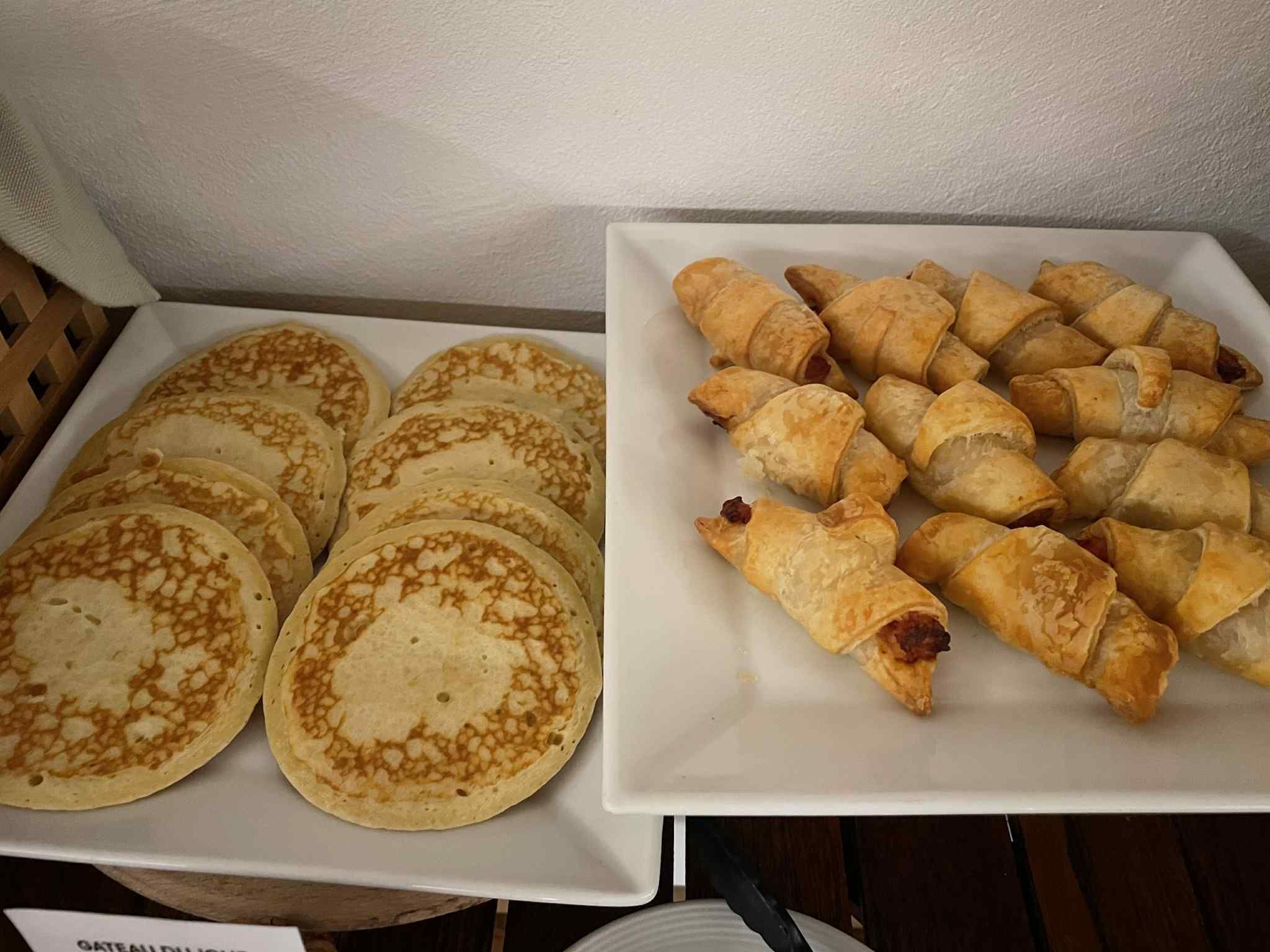 Een dienblad met eten, waaronder pannenkoeken en worstbroodjes.