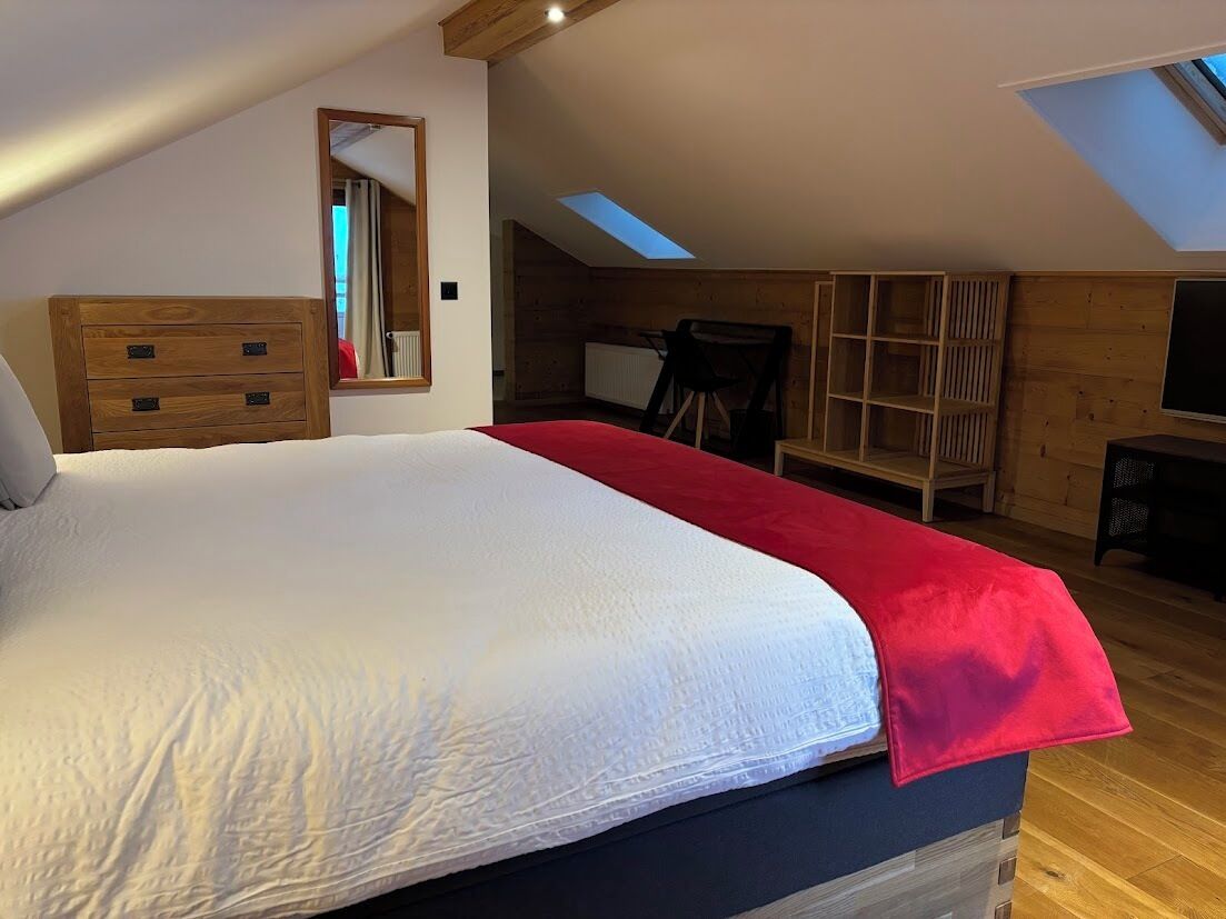 Una camera da letto con un letto grande, una cassettiera in legno e un lucernario.
