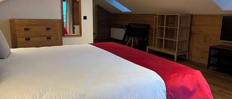 Un dormitorio con una cama grande, cómoda de madera y tragaluz.