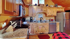 A cozy kitchen with wooden cabinets, a stainless steel refrigerator, and a coffee maker.