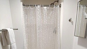 Et lille badeværelse med bruseforhæng, toilet og håndvask.