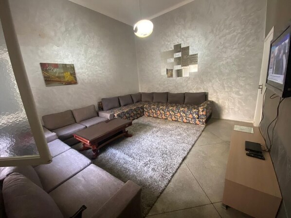 A living room with a sectional sofa, a coffee table, and a TV on a stand.