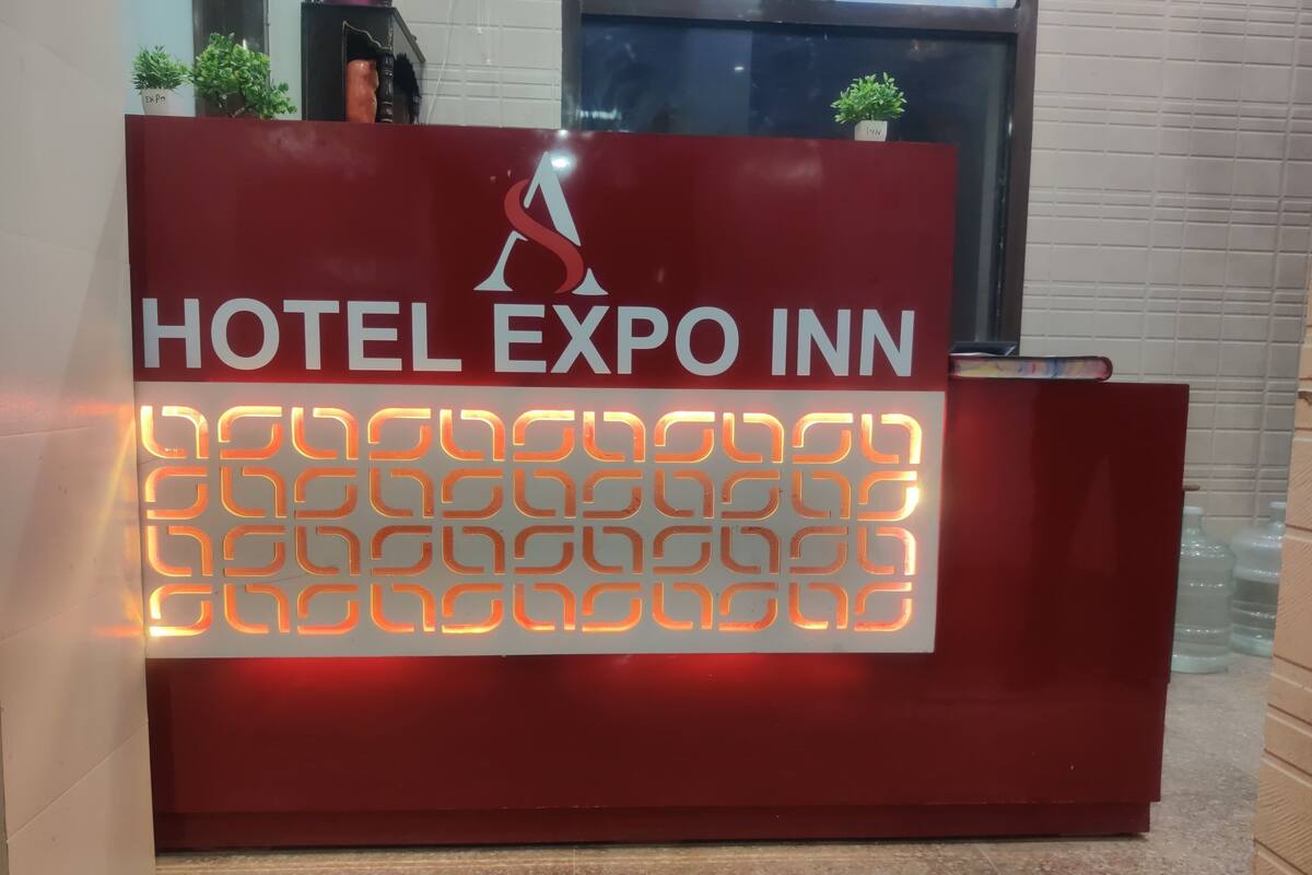 A red reception desk with the text 'HOTEL EXPO INN' and a logo above it.