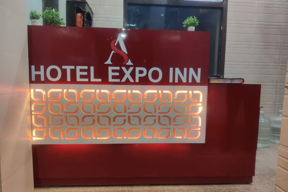A red reception desk with the text 'HOTEL EXPO INN' and a logo above it.
