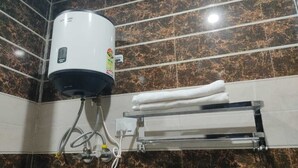 A bathroom with a water heater, towel rack, and marble tiles. - AS Hotel Expoinn (Greater Noida)