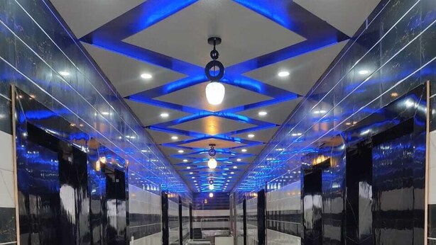 A modern, well-lit hallway with reflective floors and walls, leading to elevators. - AS Hotel Expoinn (Greater Noida)