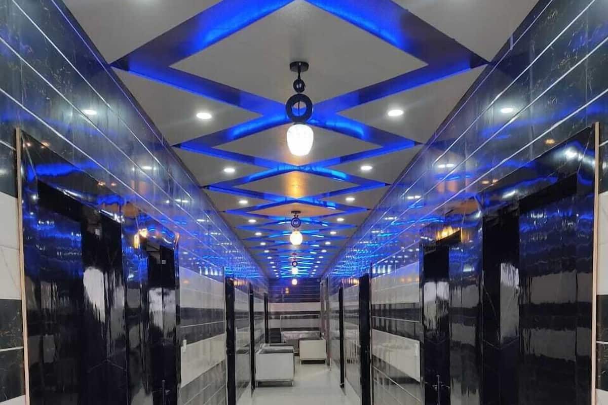 A modern, well-lit hallway with reflective floors and walls, leading to elevators.