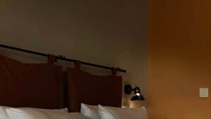 Una habitación de hotel con una cama, un cabecero y una lámpara fijada a la pared.