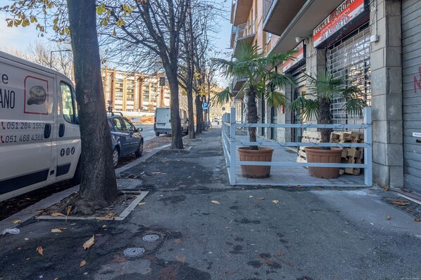 Une vue de rue avec un fourgon garé, des arbres, un trottoir et un bâtiment portant une enseigne.