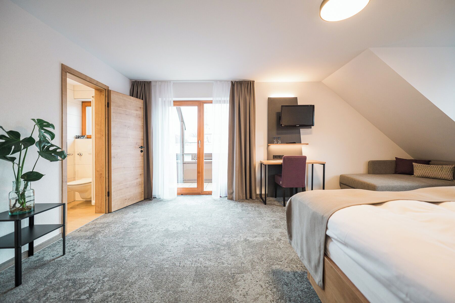 Une chambre d’hôtel moderne équipée d’un lit, d’un bureau et d’une télévision.