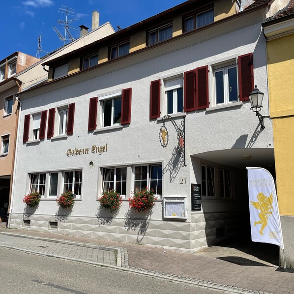 A building with the sign "Goldener Engel" and multiple windows with red shutters.
