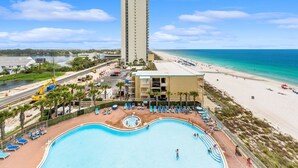 A hotel with a swimming pool, beach, and ocean view.