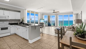 A modern kitchen with white cabinetry, a central island, and a view of the ocean through large windows.