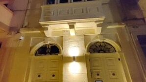 Fachada de edificio con dos puertas simétricas, cada una con un pequeño ventanal superior.