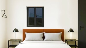 Un dormitorio con una cama, dos mesitas de noche, una ventana y una puerta.
