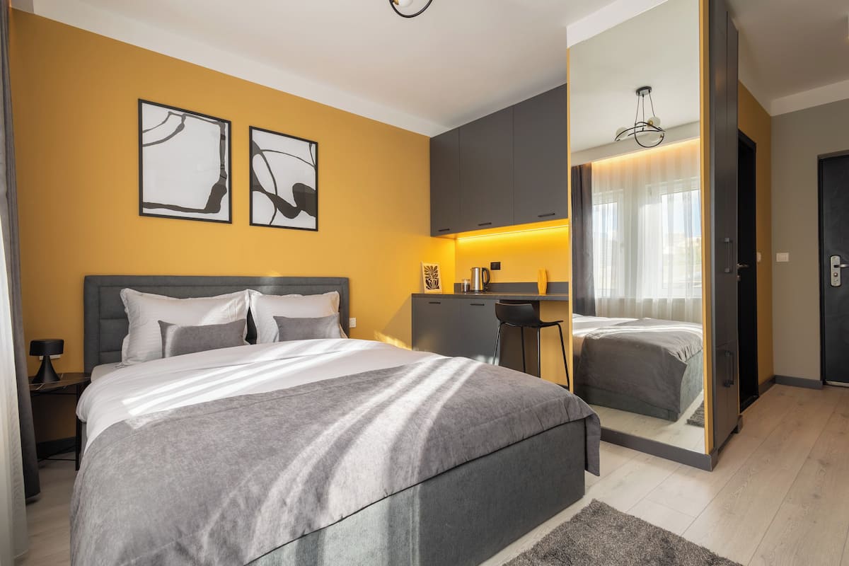 A modern bedroom with a large bed, a desk, and a mirror.