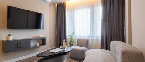 A modern living room with a flat-screen TV, a sofa, a coffee table, and a small side table.